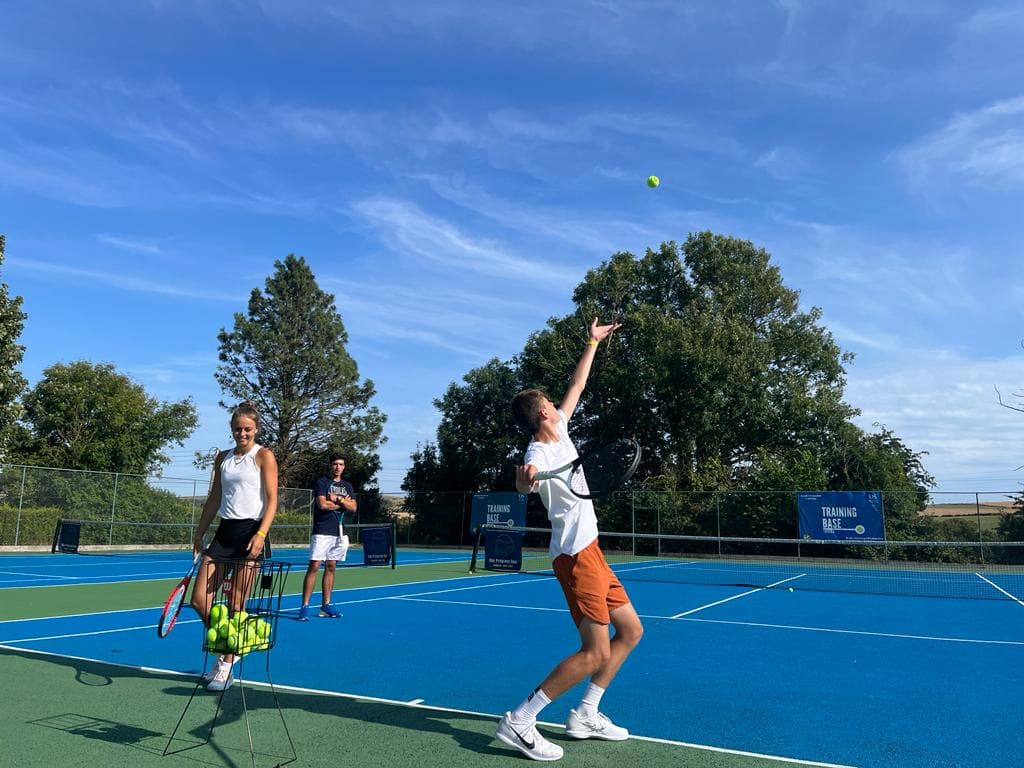 A young player tossing the ball to serve